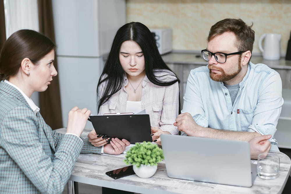 A couple sat at a desk with a mortgage advisor/broker getting advice.